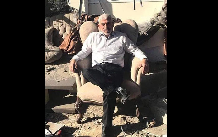 Sinwar sitting in an arm chair amongst the rubble of his house