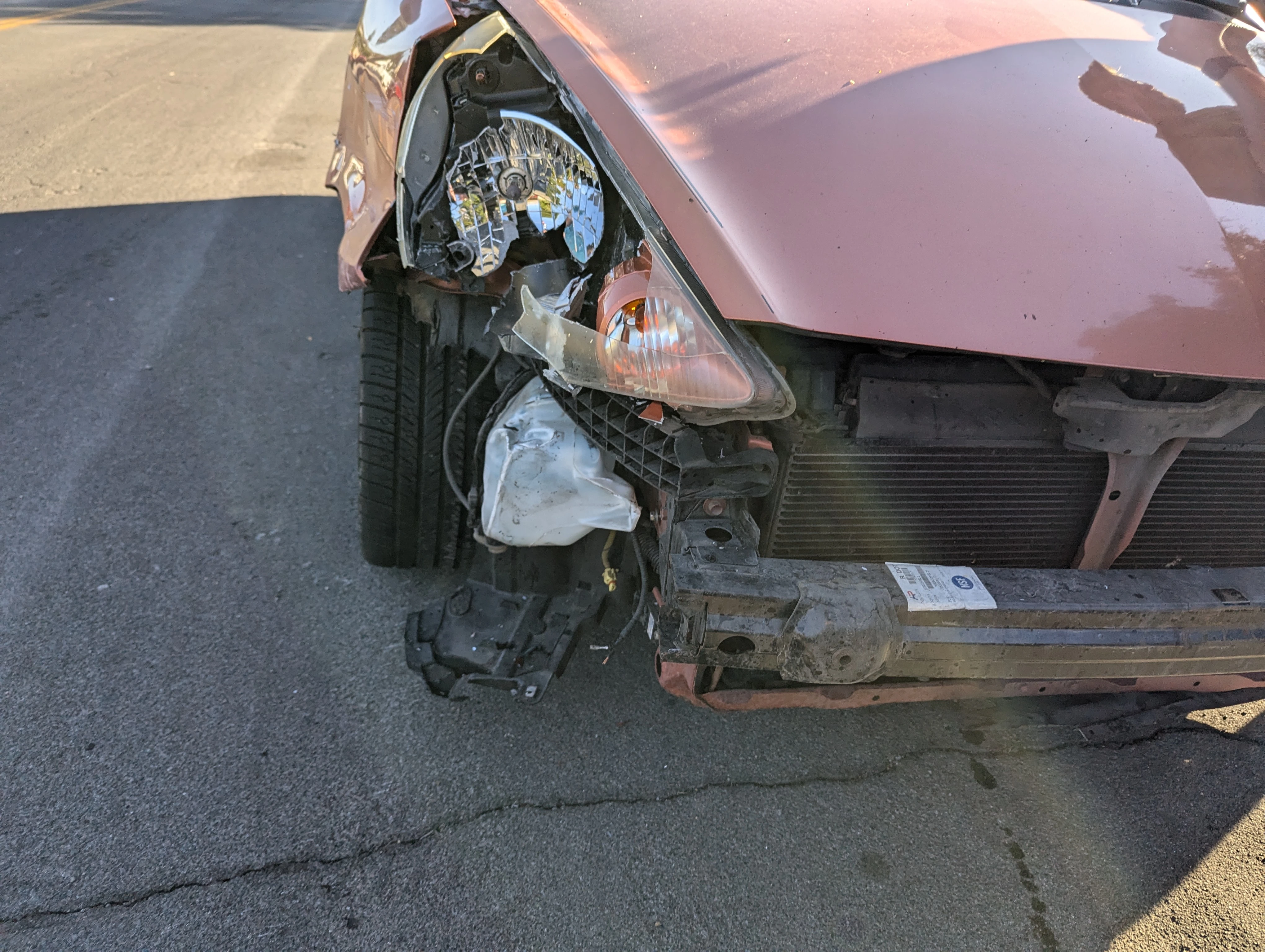 image of the front of a orange car that got crashed into and is missing the bumper