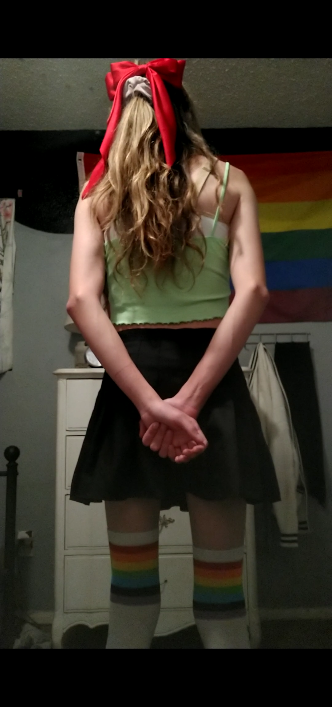 Me wearing a cute, small, green tank top along with a black skirt. Red ribbon in my hair. Facing away from camera.