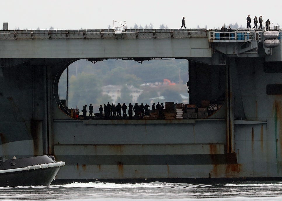 Sailors aboard the USS Nimitz are silhouetted in the hangar bay as the ship returns to Naval Base Kitsap on Sunday, Sept. 24, 2023.