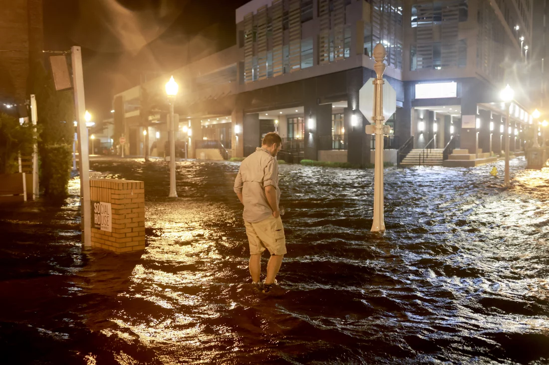 Brandon Marlow walks through surge waters flooding the street after Hurricane Milton came ashore in the Sarasota area in Fort Myers, Florida.