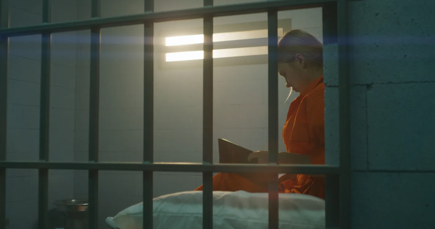 person reading book in jail cell