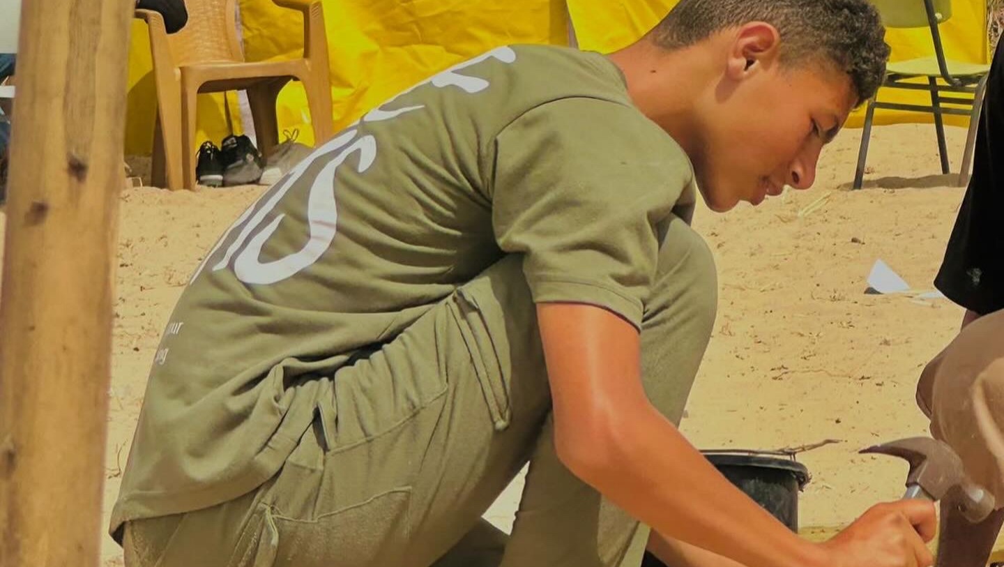 Yazan helping rebuild his family's temporary shelter, after evacuating to Al Mawasi from Rafah